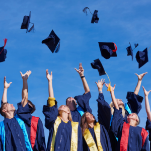 students in graduation gowns throwing caps in the air