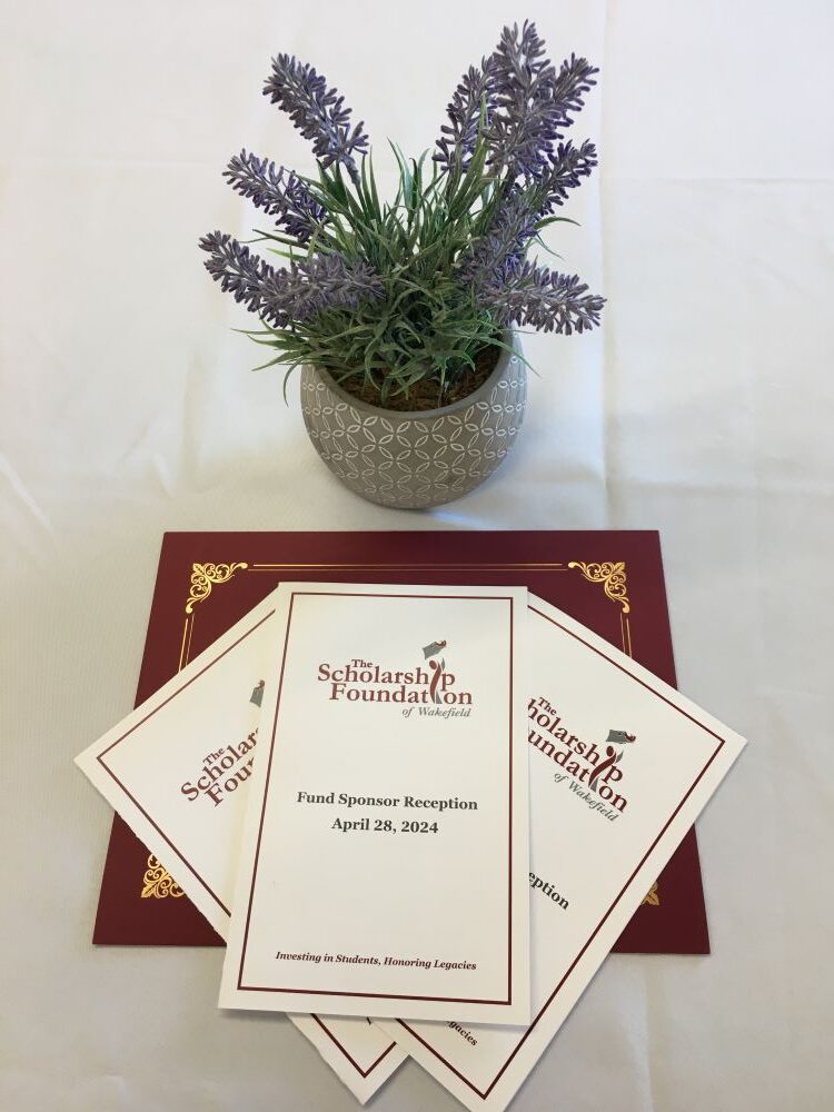 Table setting for Fund sponsor reception with small plant and programs