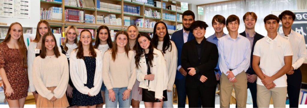 A group of students standing in front of bookshelves.